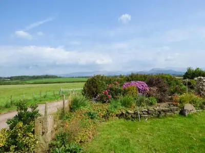 a garden with flowers and a fence in a field at Muncaster View in Drigg