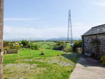 a yard with a stone building and a field at Gable View in Drigg