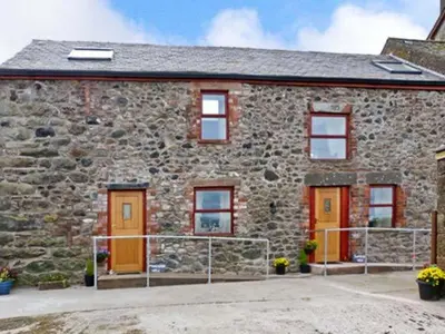 a stone house with orange doors and windows at Gable View in Drigg