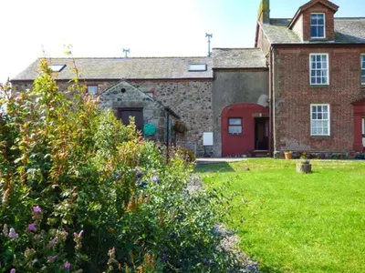 a large brick house with a green yard with flowers at Gable View in Drigg