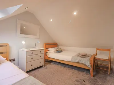 a bedroom with two beds and a dresser and a chair at South Milton Cottage in Glenluce