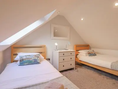 a attic bedroom with two beds and a dresser at South Milton Cottage in Glenluce