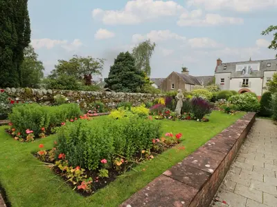 a garden with flowers and a stone wall at The Old Brewery Store in Gatehouse of Fleet