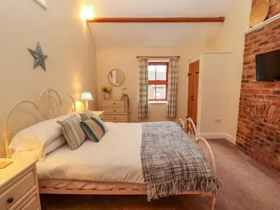 a bedroom with a bed and a brick wall at The Old Bothy in Wigton