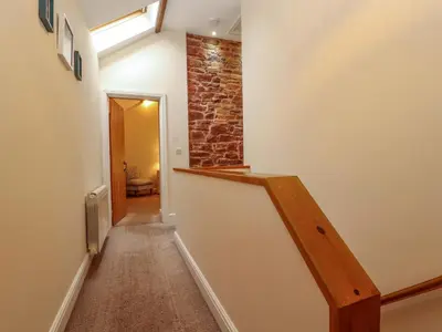 a hallway with a staircase with a brick wall at The Old Bothy in Wigton