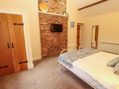 a bedroom with a bed and a brick wall at The Old Bothy in Wigton