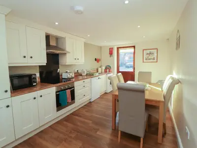 a kitchen with white cabinets and a wooden table with a wooden floor at The Old Grainstore in Wigton