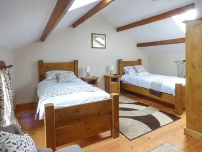 two beds in a room with wooden floors at Fell View Cottage in Bootle