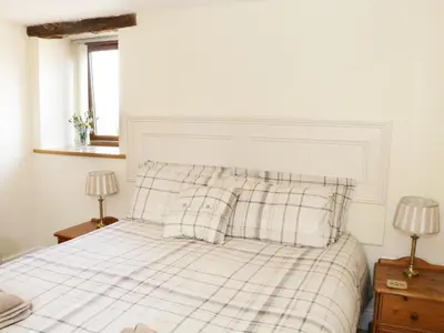 a bedroom with a bed with plaid sheets and two lamps at Piggery Cottage in Wigton