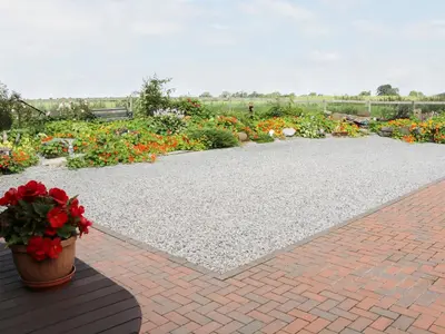 a flower garden with a pot of red flowers at Piggery Cottage in Wigton