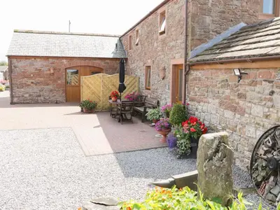 an outdoor patio with a table and chairs and a building at Piggery Cottage in Wigton