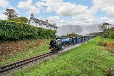 a train traveling down the tracks near a house at Peel Place Noddle in Eskdale
