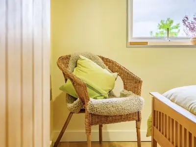 a wicker chair with green pillows in a bedroom at Solway Cottage in Bowness-on-Solway