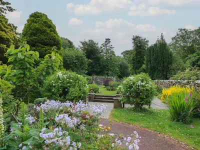 a garden with a bench and many flowers at 79 Laurel Bank in Gatehouse of Fleet