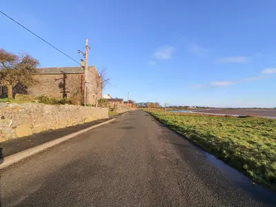 an empty road next to a stone wall at Sonya's Cottage in Anthorn