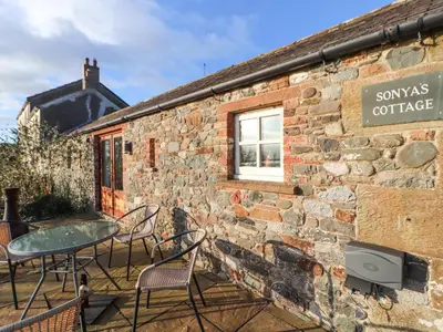 a brick building with a table and chairs outside at Sonya's Cottage in Anthorn