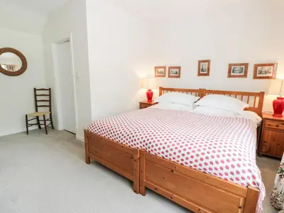 a bedroom with a bed with a red and white comforter at The Mews Flat in Dalswinton