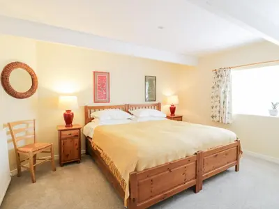 a bedroom with a bed and a chair and a window at The Mews Flat in Dalswinton