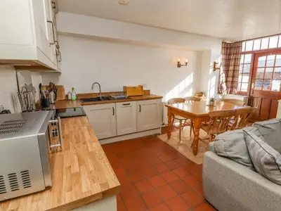 a kitchen and dining room with a table and a couch at Mellfell Cottage in Watermillock