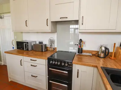 a kitchen with white cabinets and a stove top oven at Mellfell Cottage in Watermillock