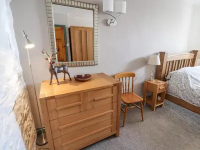 a bedroom with a dresser with a mirror and a bed at Mellfell Cottage in Watermillock