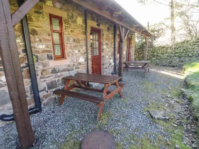 a picnic table sitting outside of a stone building at Mellfell Cottage in Watermillock