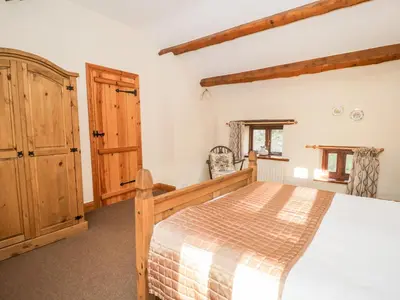 a bedroom with a bed and a wooden cabinet at Stable End Cottage in Nether Wasdale