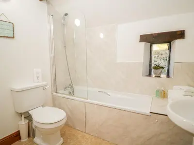 a bathroom with a toilet and a tub and a sink at Stable End Cottage in Nether Wasdale