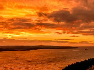 a sunset over a body of water with a boat at Little Laight in Cairnryan