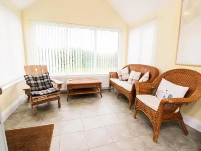 a living room with wicker chairs and a table at Simmer Dim in Kirkbean