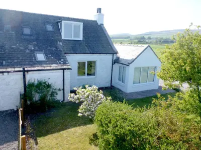 a view of a white house with a yard at Simmer Dim in Kirkbean