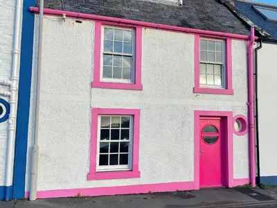 a pink and white house with a red door at The Pink House in Isle of Whithorn