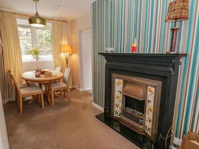 a living room with a fireplace and a table at Nathaniel's Cottage in Kirkcudbright