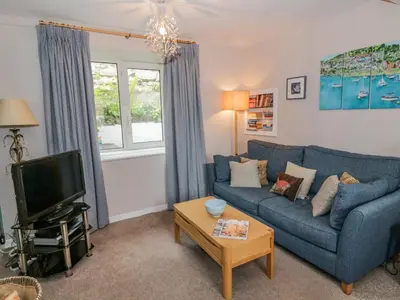 a living room with a blue couch and a tv at Nathaniel's Cottage in Kirkcudbright