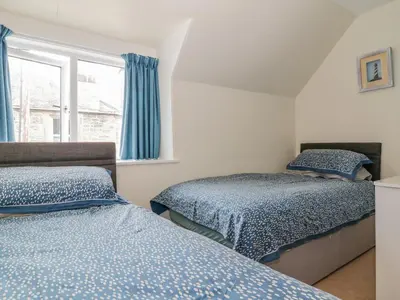 a bedroom with two beds and a window at Nathaniel's Cottage in Kirkcudbright