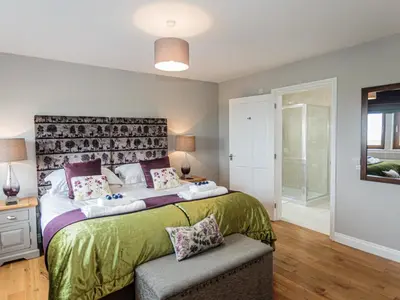 a bedroom with a large bed with a large headboard at Corsewall Castle Farm Lodges in Kirkcolm