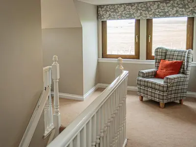 a stairway with a chair and a window at Corsewall Castle Farm Lodges in Kirkcolm