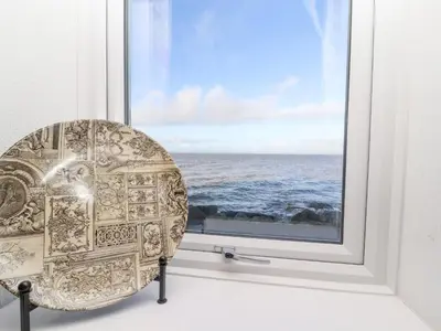 a chair sitting in a window looking at the ocean at Greenmantle in Skinburness