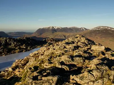a rocky mountain with snow covered mountains in the background at Littlebeck in Rosthwaite