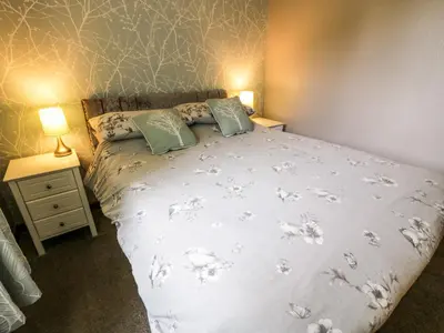 a bedroom with a white bed with two pillows at Torkeld Holiday Cottage in Garlieston