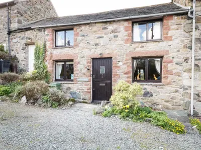 a stone house with a black door and windows at Barn Roost in Uldale