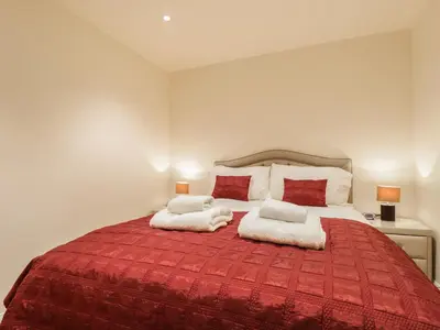 a bedroom with a large red bed with two pillows at Wrenville in Keswick