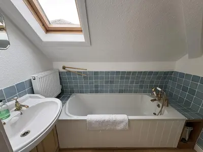 a bathroom with a white tub and a sink at Prospect Lodge in Portinscale