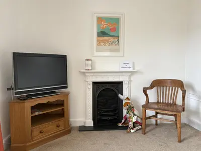 a living room with a tv and a chair and a fireplace at Prospect Lodge in Portinscale