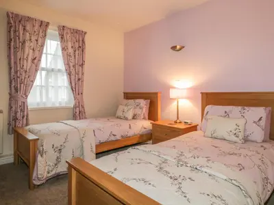 a bedroom with two beds and a window at Ale Cottage in Ireby