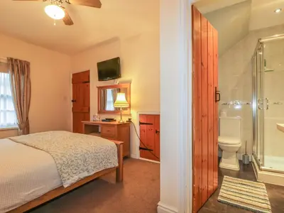 a bedroom with a bed and a shower and a toilet at Ale Cottage in Ireby