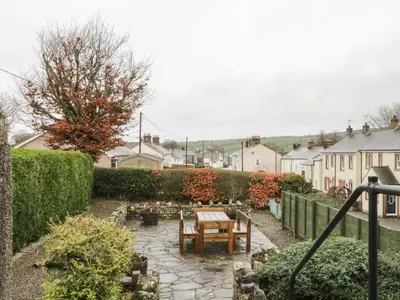 a garden with a wooden table and a bench at Ale Cottage in Ireby