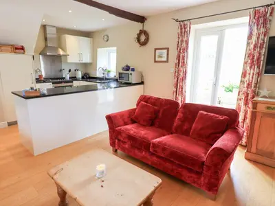 a living room with a red couch and a kitchen at Mell View Cottage in Watermillock