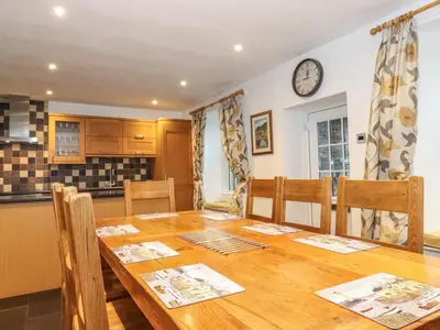 a dining room with a wooden table and a clock on the wall at Coombe Cottage in Borrowdale Valley