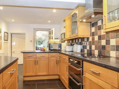 a kitchen with wooden cabinets and black counter tops at Coombe Cottage in Borrowdale Valley